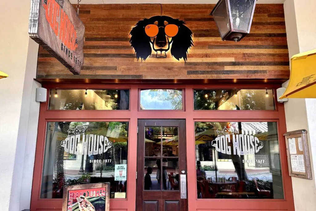 The front of The Dog House restaurant in Pensacola, Florida, with its wooden facade, features a logo of a dog's head wearing sunglasses.