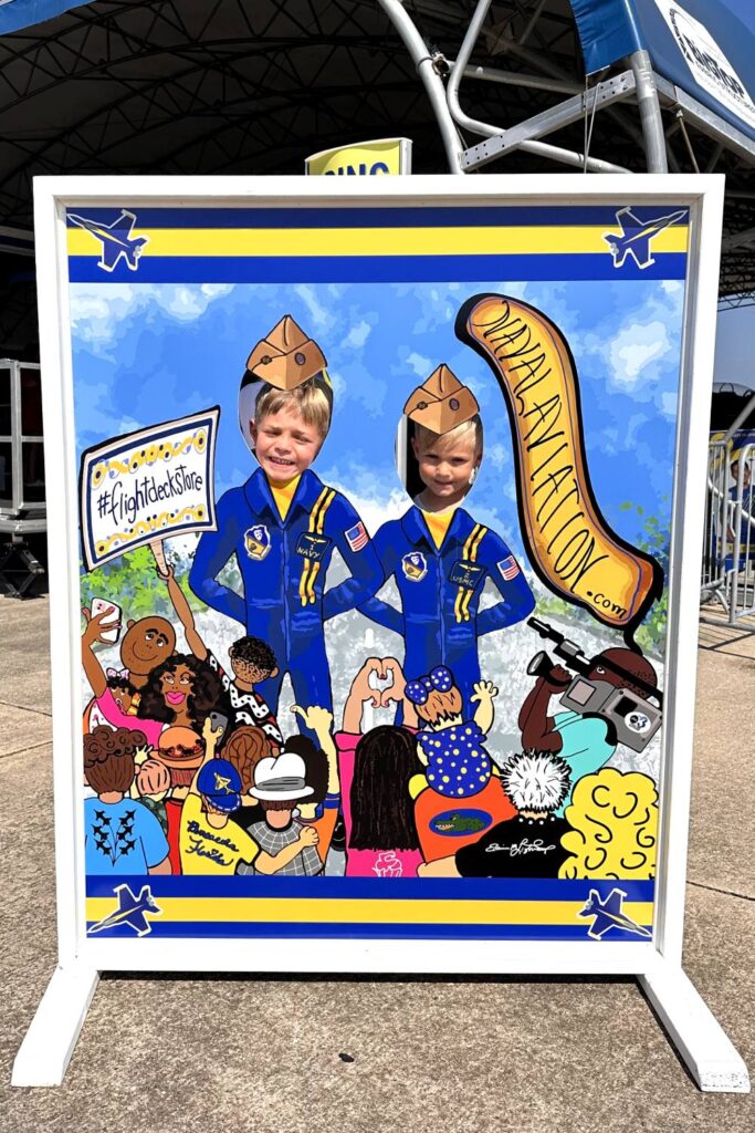 Two young boys smiling with their faces in cut-out standees dressed as Blue Angels pilots at a photo booth display. National Naval Aviation Museum, Pensacola, Florida