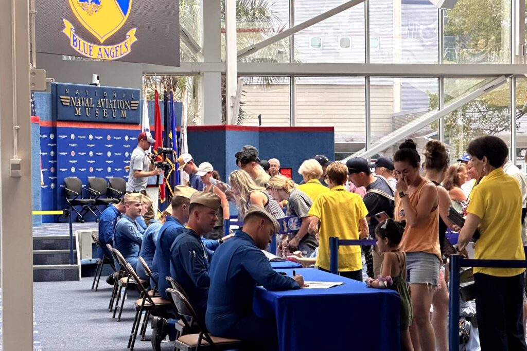 A group of Blue Angels pilots signing autographs for a crowd of visitors inside the National Naval Aviation Museum, Pensacola, Florida