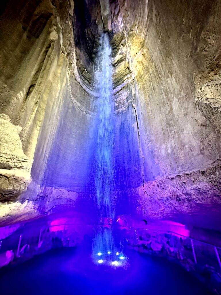 Ruby Falls waterfall illuminated by purple and blue lights, cascading down into a pool below. Ruby Falls cave walk, Chattanooga, Tennessee