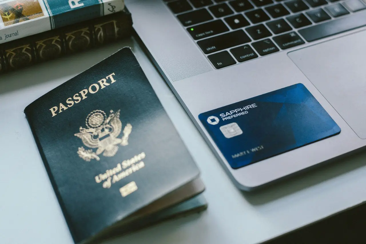 Close-up of a U.S. passport, Chase Sapphire Preferred® card, and a laptop on a desk, representing essential tools for travel planning and rewards.