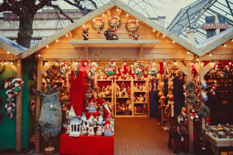 A festive wooden stall decorated with Christmas lights, wreaths, and holiday crafts at a European Christmas market. Best Christmas Markets in Europe