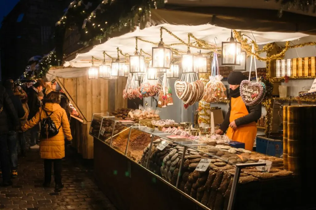 A stall at a Christmas market selling traditional German sweets, such as gingerbread hearts and baked treats, with festive decor. Nuremberg Christmas Market