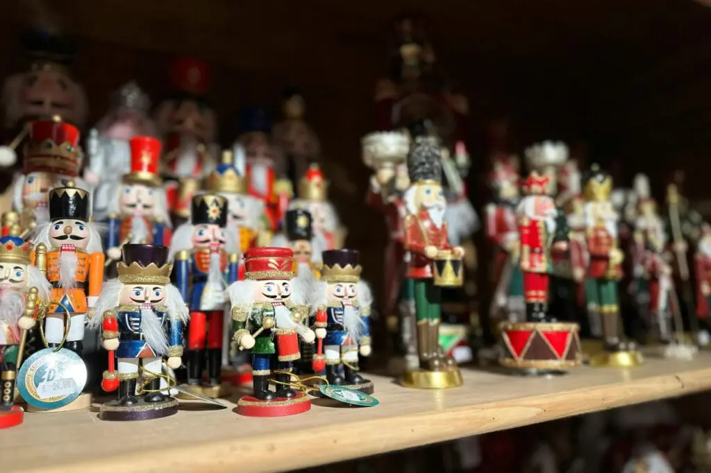 A shelf filled with colorful wooden nutcracker figurines, a classic Christmas decoration, at a market stall in Strasbourg, France.