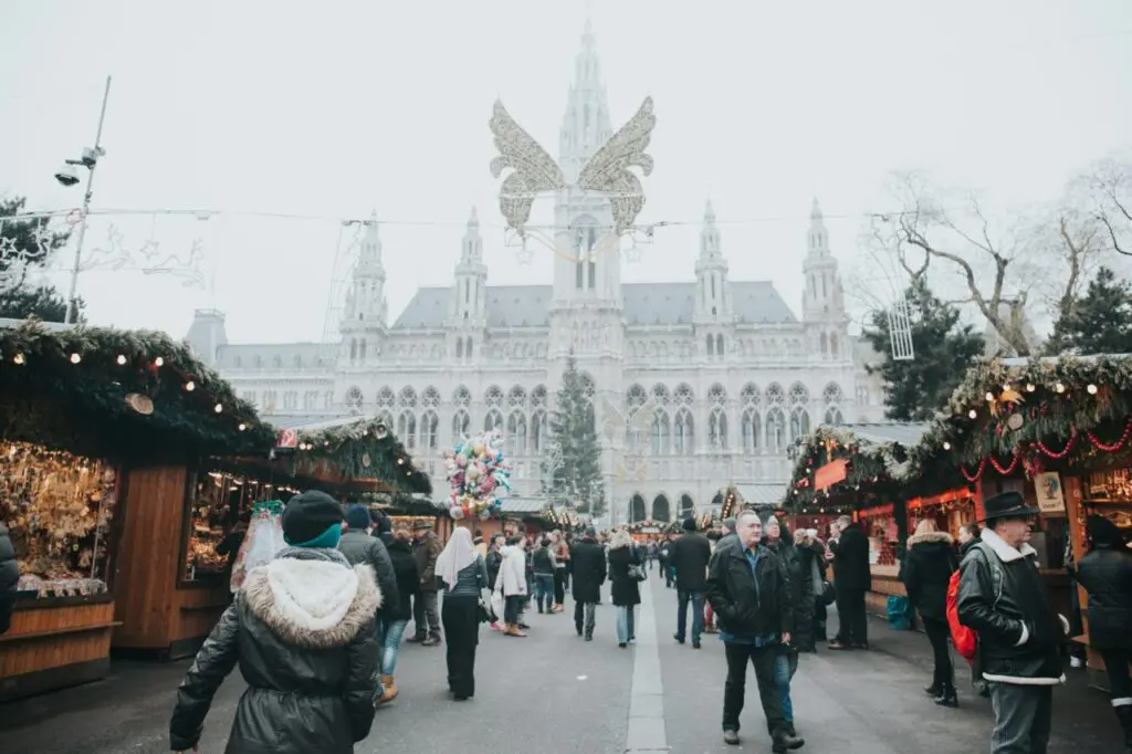 A view of Vienna’s Rathausplatz Christmas market with people browsing the stalls in front of the illuminated town hall.