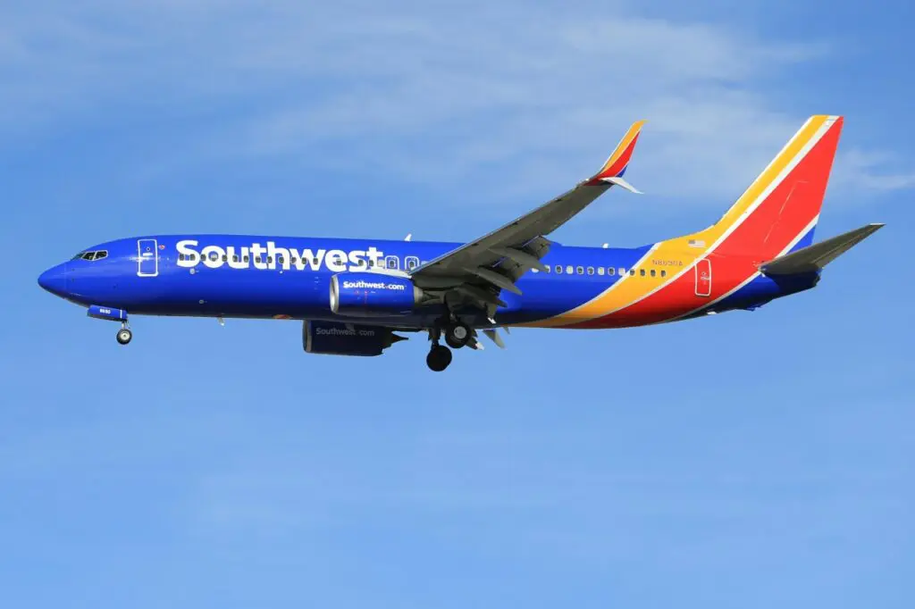 A Southwest Airlines plane in flight, captured against a clear blue sky, with landing gear deployed. Southwest Companion Pass