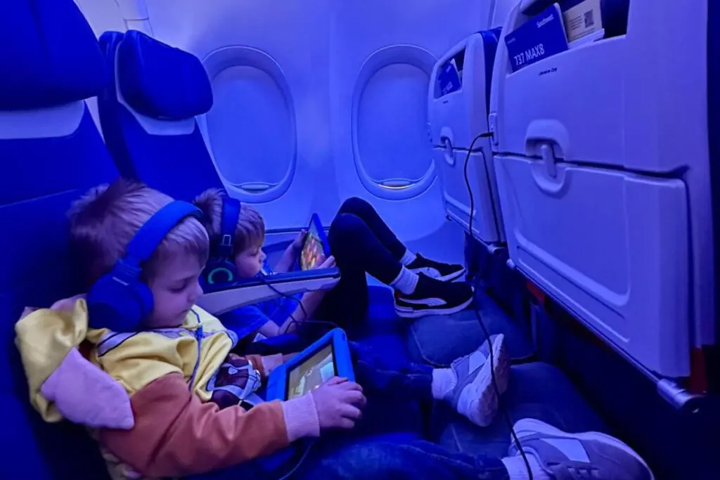 Two young children, wearing headphones, are comfortably seated on a Southwest plane.