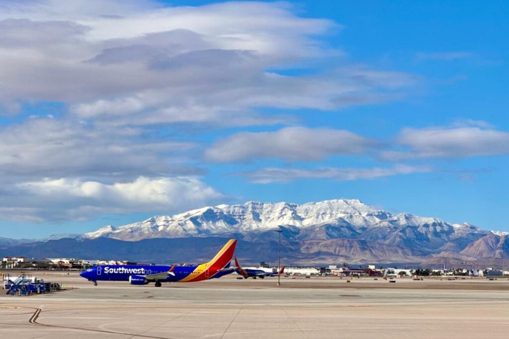 A Southwest Airlines plane an an airport runway with mountains in the background.