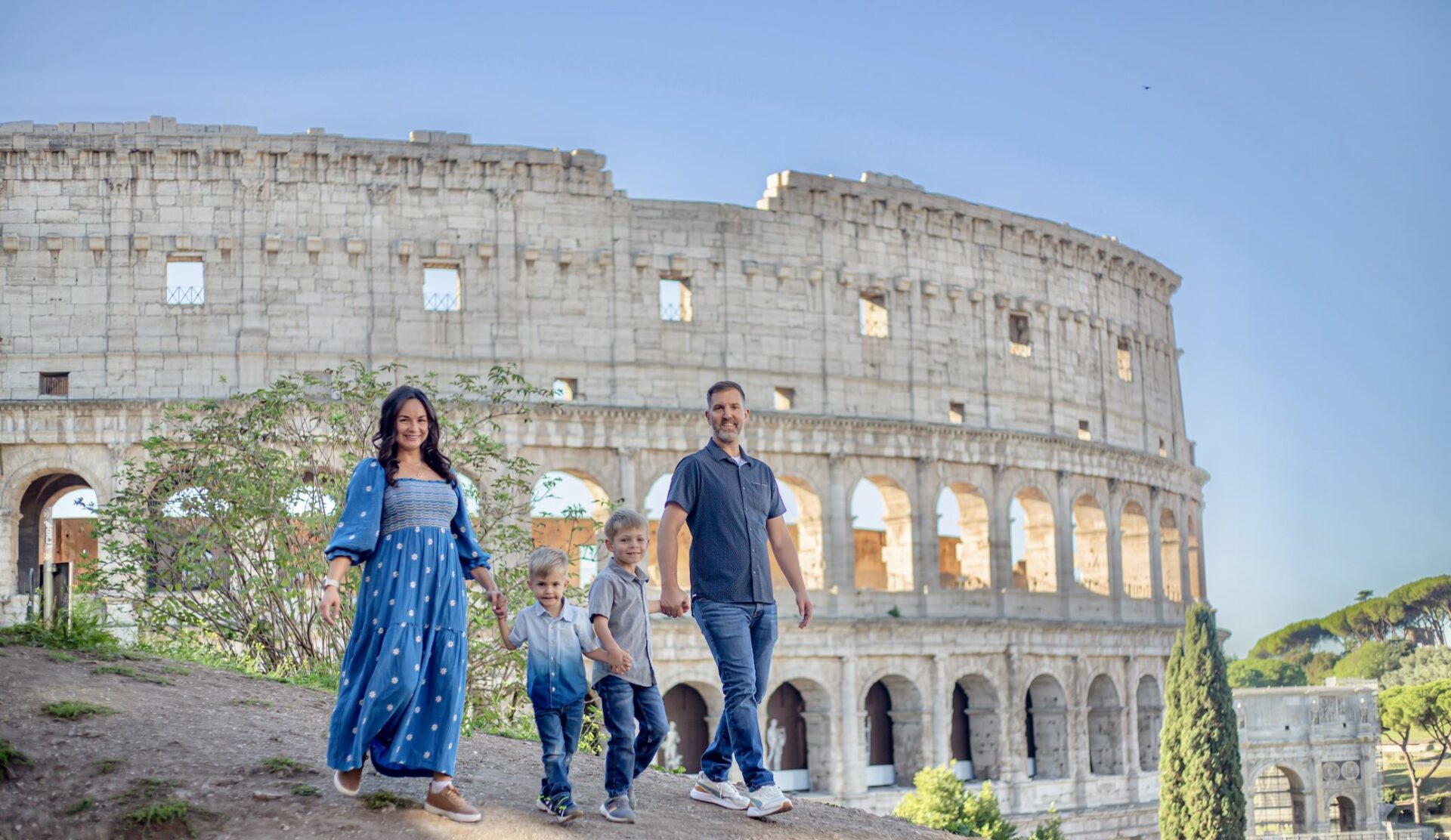 Family of four walking in front of the Colosseum in Rome, Italy