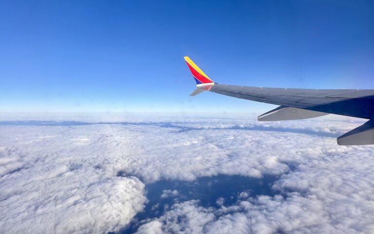 A Southwest plane wing flying over a blue sky with clouds