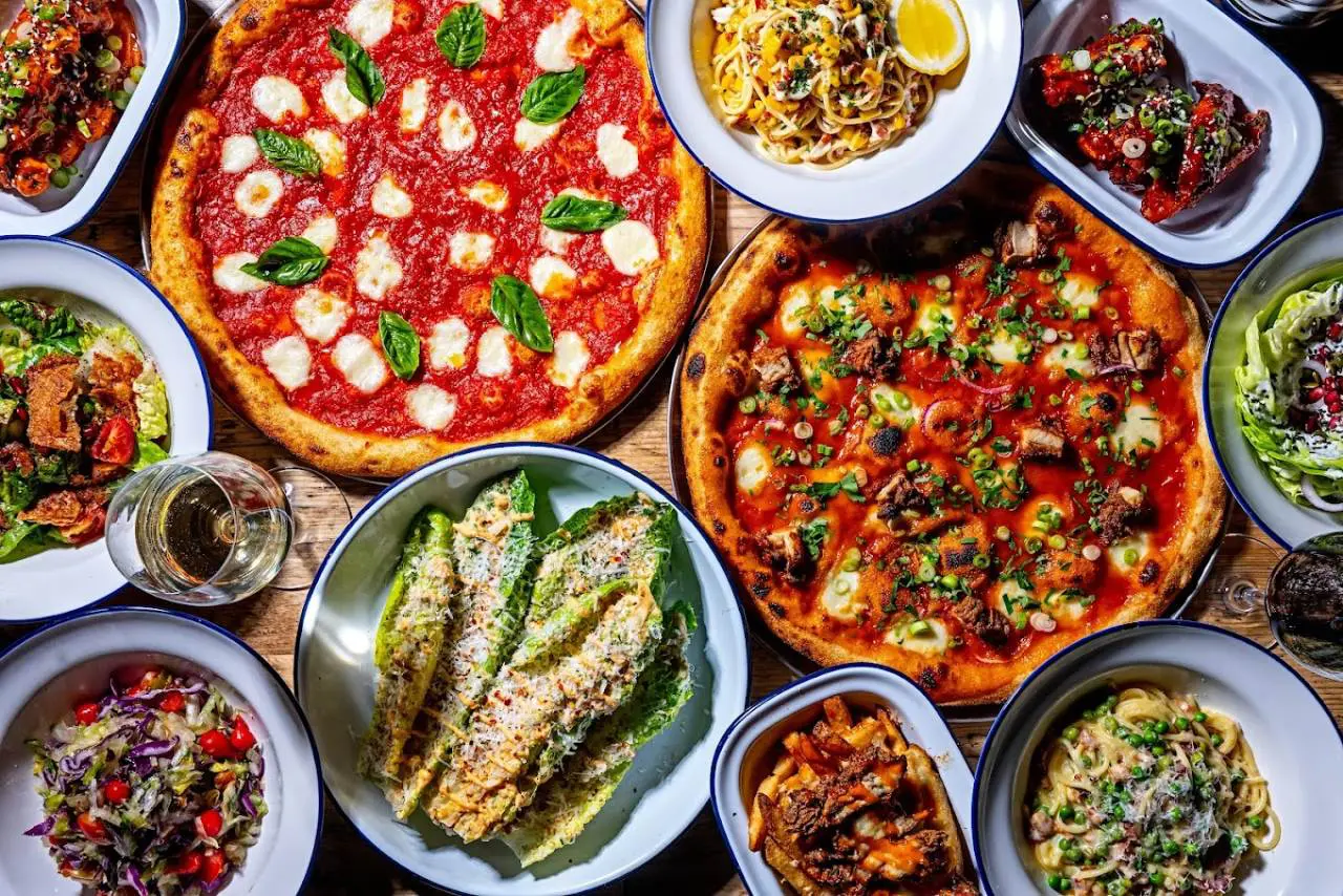 A spread of Italian dishes on a wooden table. Gordon Ramsay Street Pizza