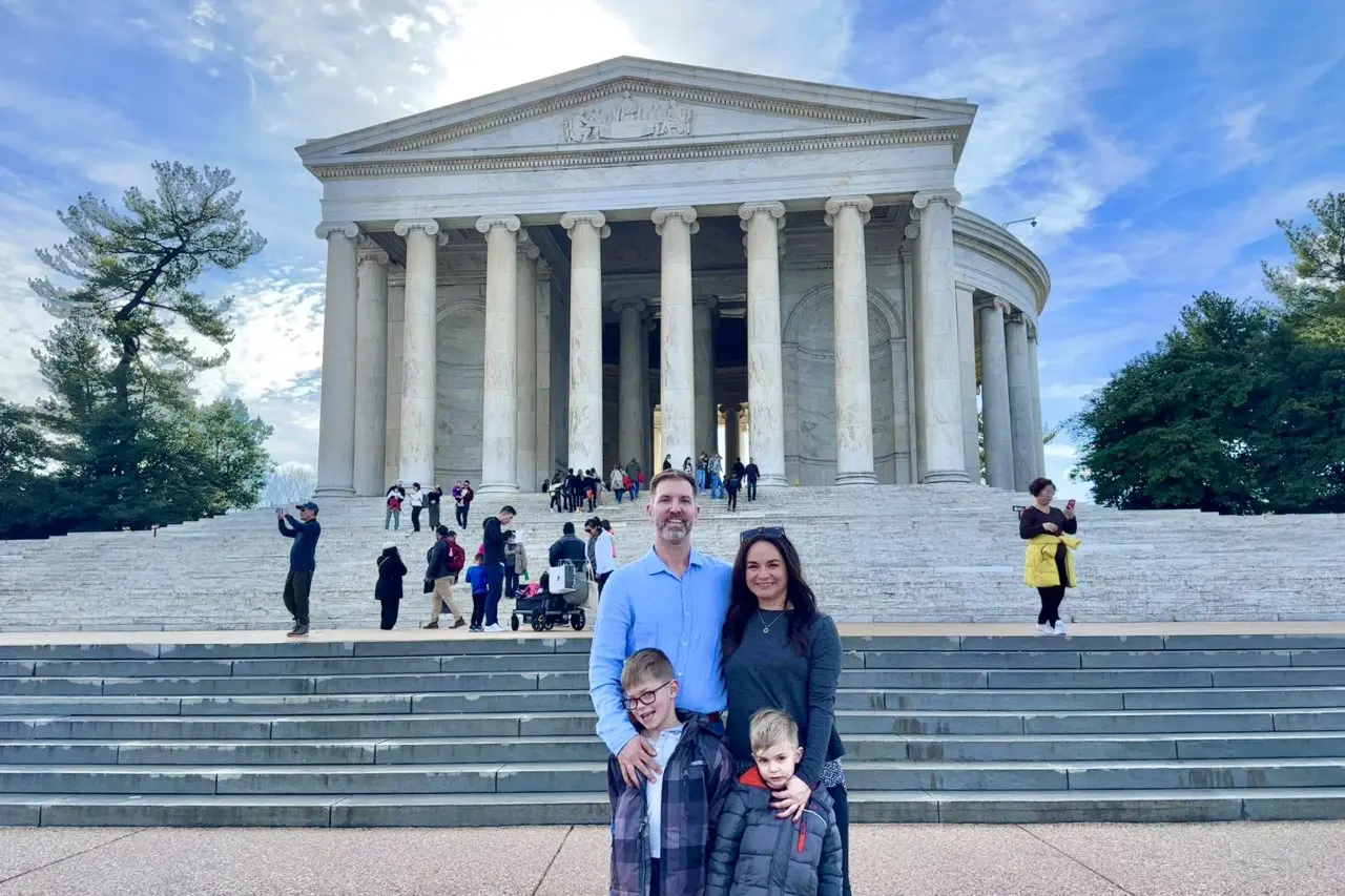 A family posing in front of the Thomas Jefferson Memorial in Washington, DC, with the grand marble columns and steps behind them.