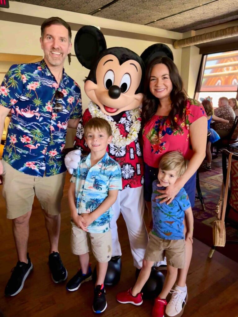 A family of four posing with Mickey Mouse at the ʻOhana character breakfast.