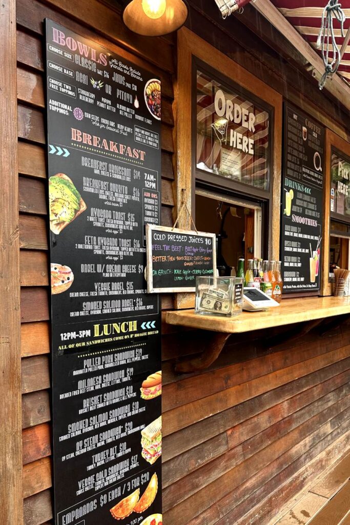 Menu board at Jaws Country Store displaying breakfast and lunch options, with cold-pressed juice options and additional food items listed. Maui, Hawaii.