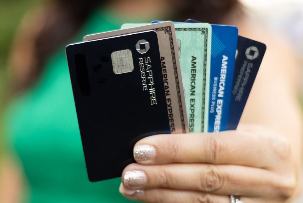 A person holding several premium travel credit cards, including Chase Sapphire and American Express, fan-style in their hand.