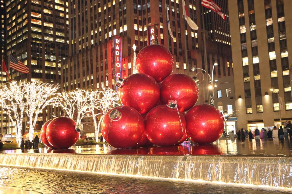 Giant red Christmas ornaments on display by the fountain near Radio City Music Hall in New York City during the holidays.