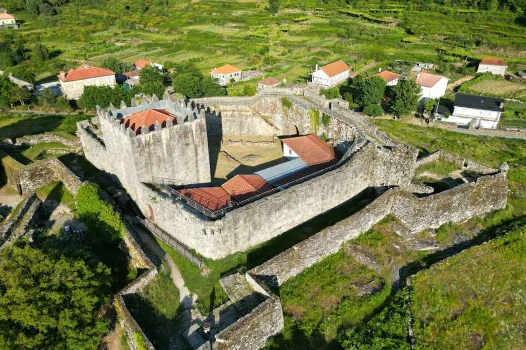 Aerial view of the medieval Lindoso Castle surrounded by terraced vineyards and green hills in northern Portugal