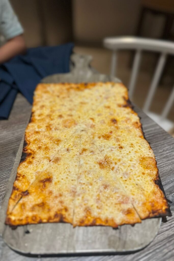 A rectangular cheese pizza fresh from the oven at Pizza Lab inside the Grand Hyatt Baha Mar, served on a metal tray.