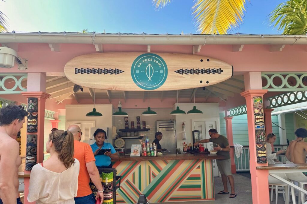 Da' Poke Bowl food truck at Baha Bay water park, with guests lining up under a surfboard sign and colorful tiki-style decor in Nassau, Bahamas.
