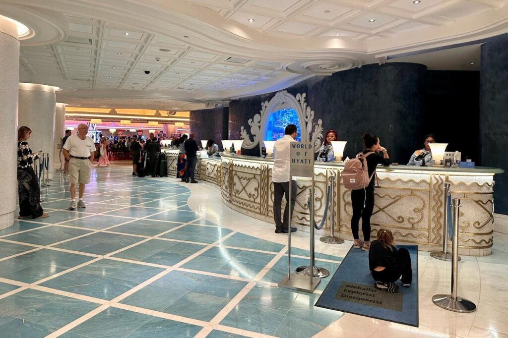 The World of Hyatt check-in desk at Grand Hyatt Baha Mar with a dedicated Globalist, Explorist, and Discoverist lane sign, and the casino visible in the background.