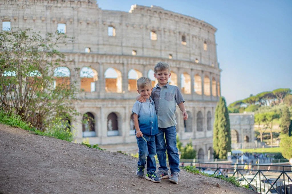 Two brothers standing together in front of the Colosseum and the Arch of Constantine