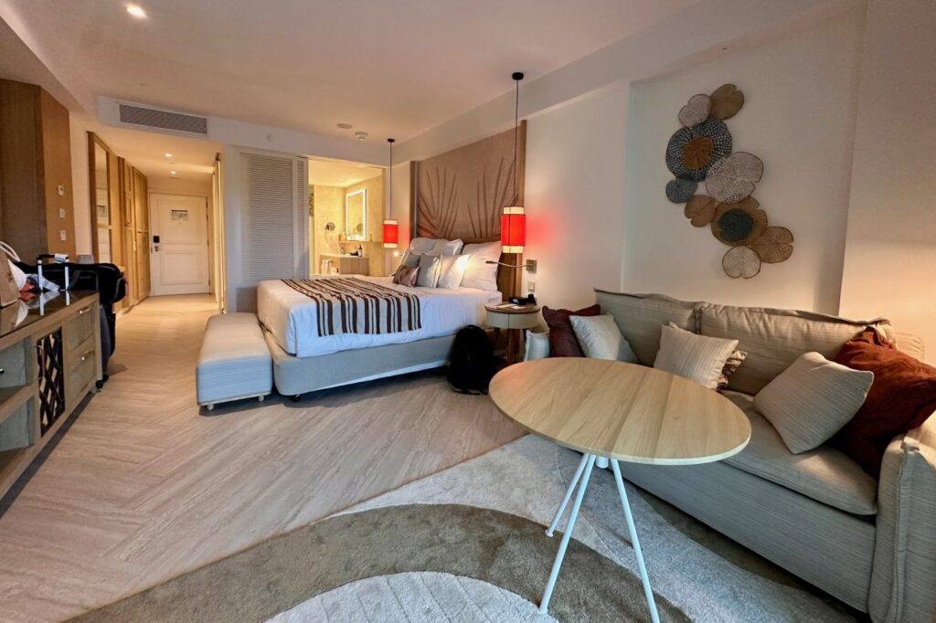 Spacious hotel room at Dreams Playa Esmeralda with king bed, sofa, round coffee table, and warm lighting