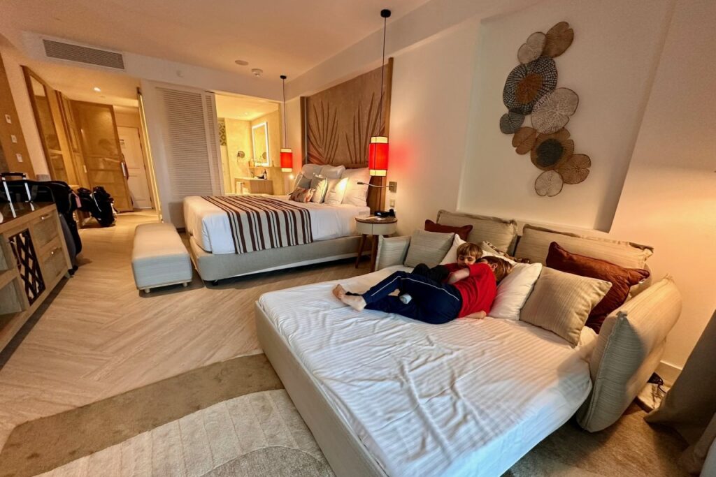 Two kids lounging on the pullout sofa bed in the hotel room at Dreams Playa Esmeralda