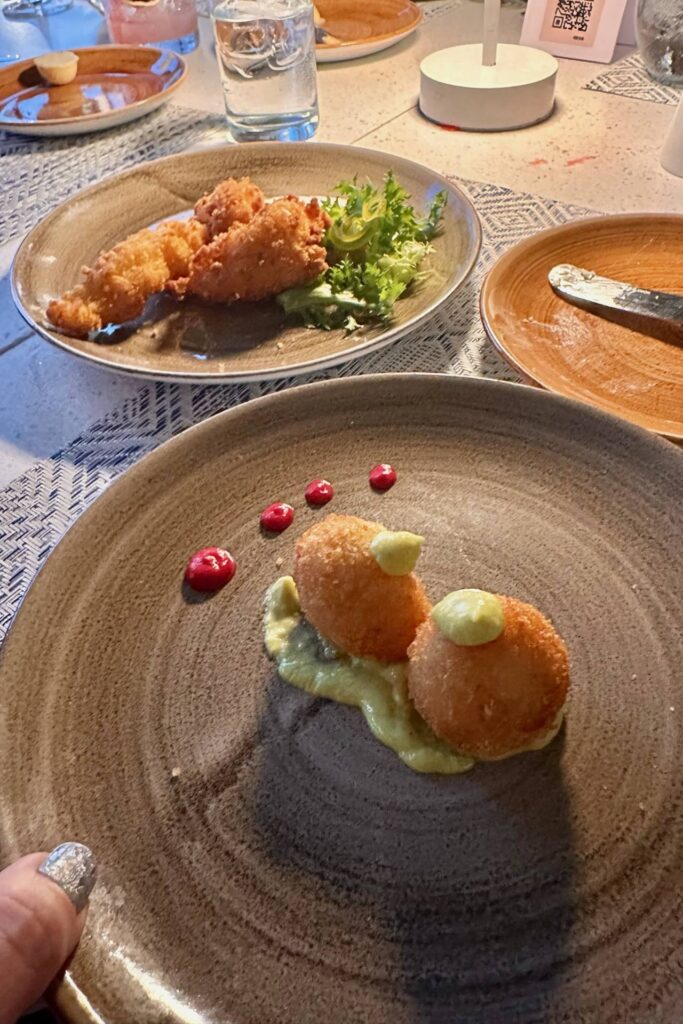 Plated appetizers at Tierra including fried bites with avocado sauce and crispy fish with greens