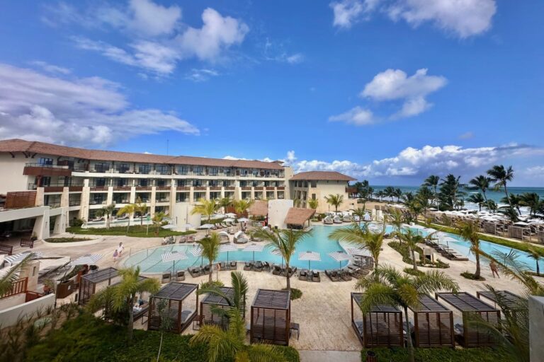 Aerial view of Dreams Playa Esmeralda resort showing the pool area, palm trees, cabanas, and ocean beyond