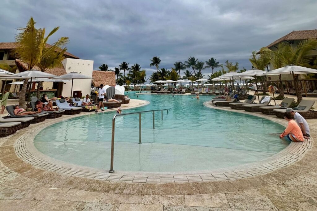 Main resort pool at Dreams Playa Esmeralda with lounge chairs, umbrellas, and thatched swim-up bar