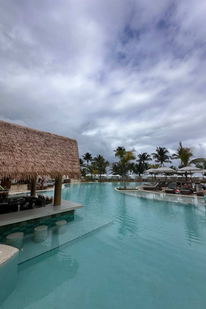 Swim-up bar at Dreams Playa Esmeralda with thatched roof, submerged bar stools, and palm trees in the background