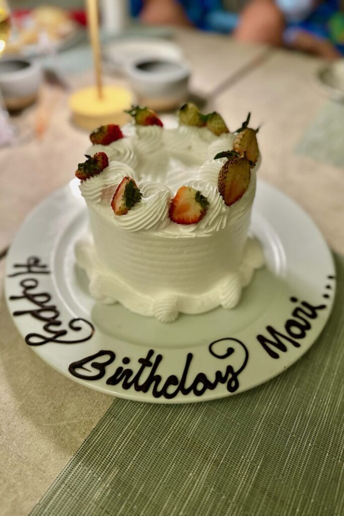 Small birthday cake topped with strawberries on a plate reading "Happy Birthday Mari" at Dreams Playa Esmeralda