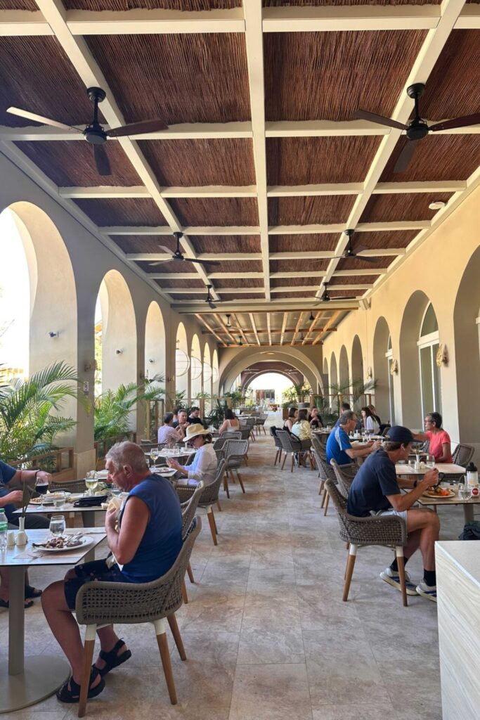 Open-air restaurant dining terrace at Dreams Playa Esmeralda with arched columns, thatched ceiling, and guests seated for dinner