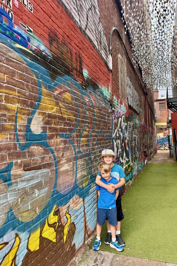 Two brothers posing in a colorful graffiti alley while exploring Chattanooga with kids