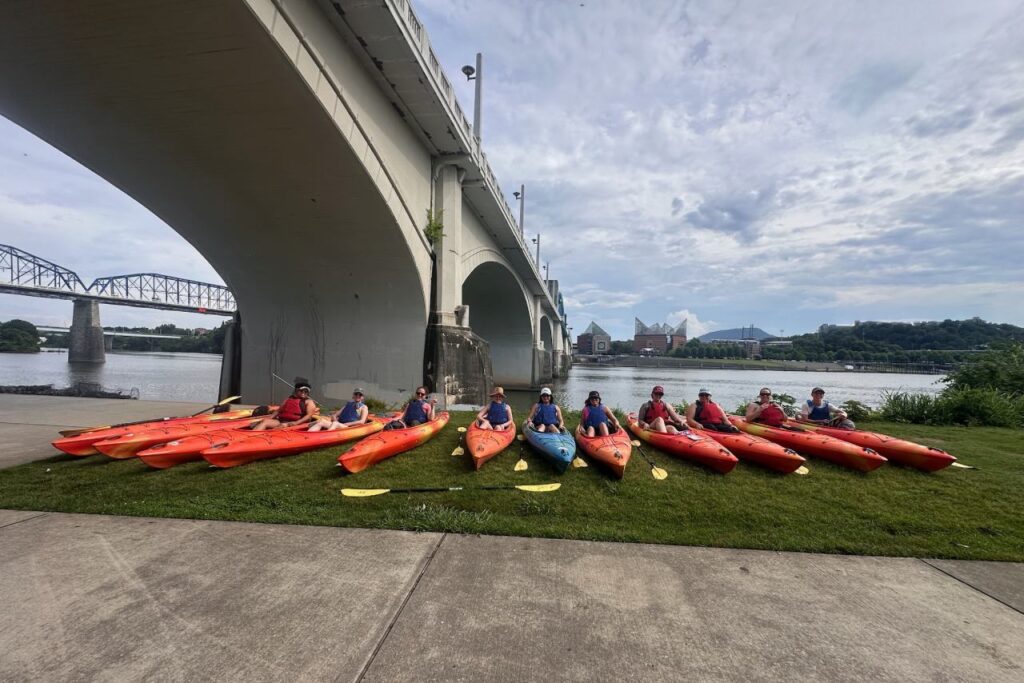Kayakers lined up along the Tennessee River below a downtown Chattanooga bridge