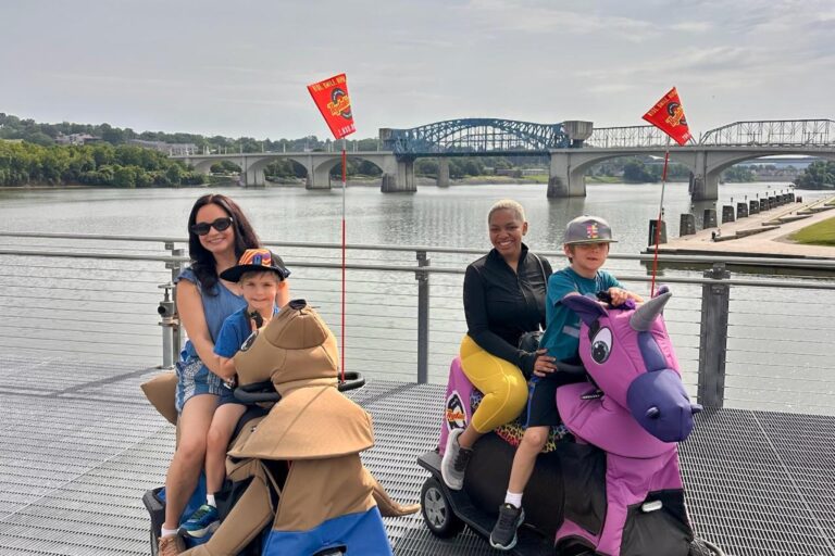 Family riding Rydables along the riverfront with a Chattanooga bridge in the background