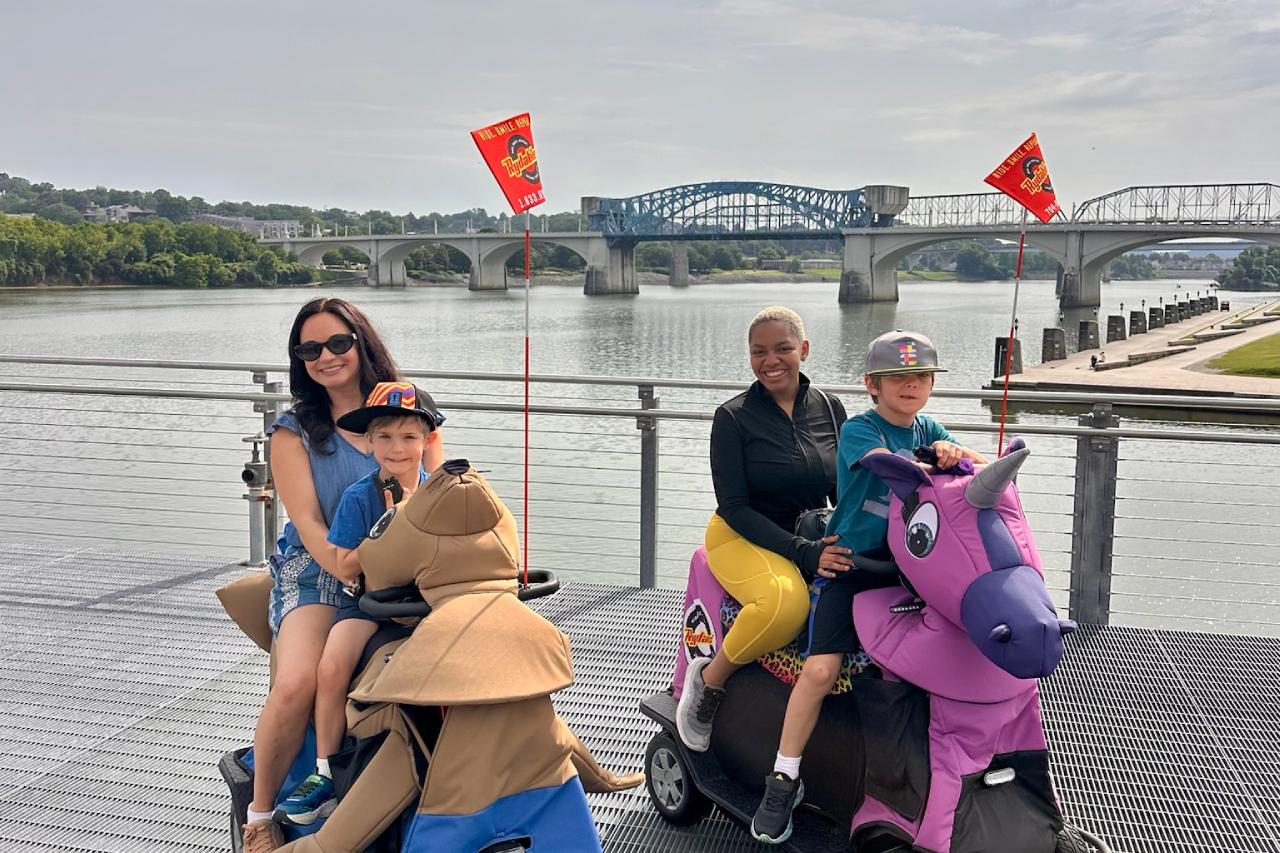 Family riding Rydables along the riverfront with a Chattanooga bridge in the background