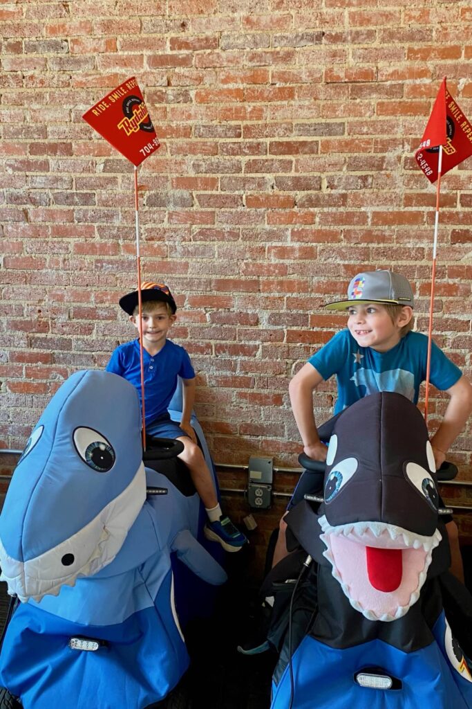 Two boys riding shark and orca Rydables against an exposed brick wall in Chattanooga
