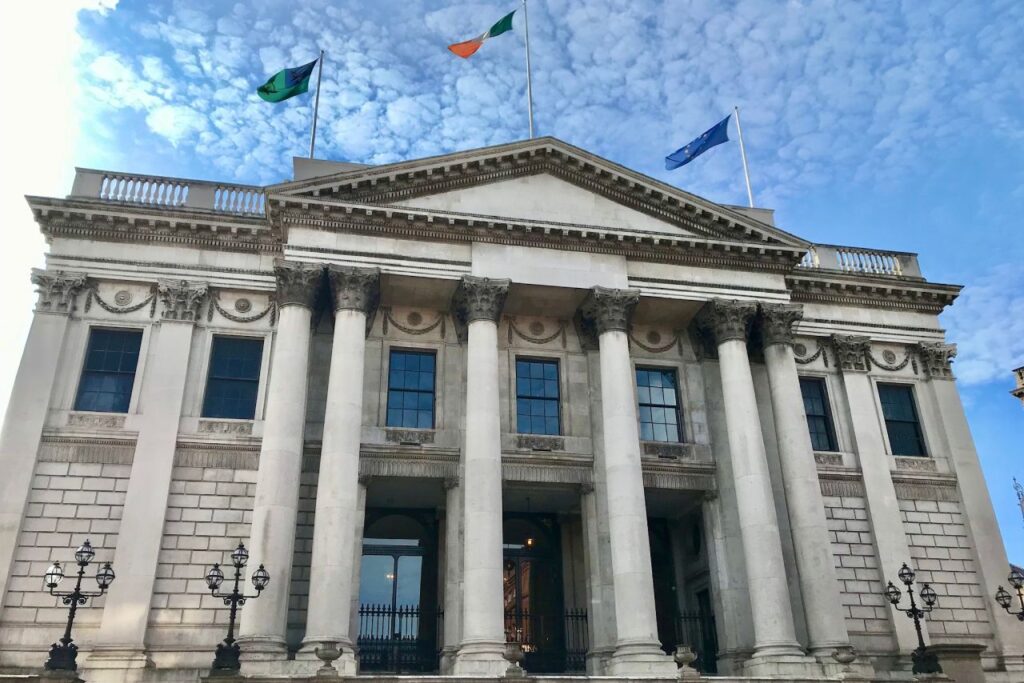Neoclassical civic building with Corinthian columns in Dublin, Ireland, flying the Irish tricolour and EU flag.