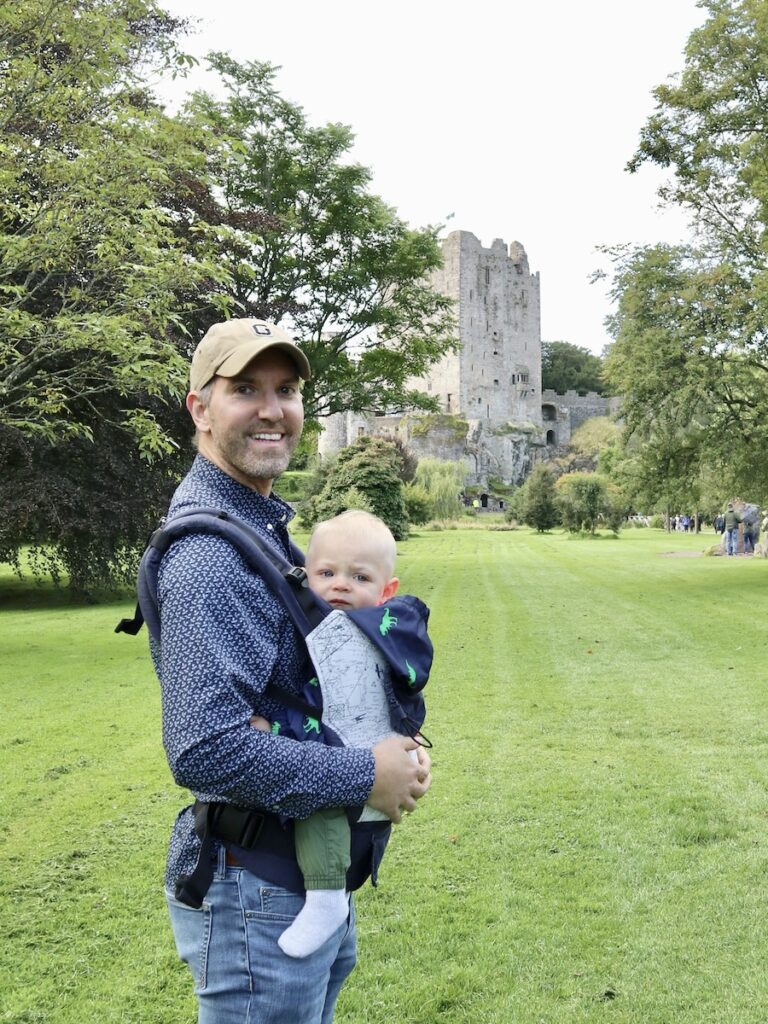 A man holds a baby in a carrier at Blarney Castle Ireland