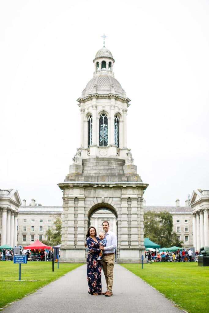 Family of three stands in front of a spire at Trinity College Dublin Ireland