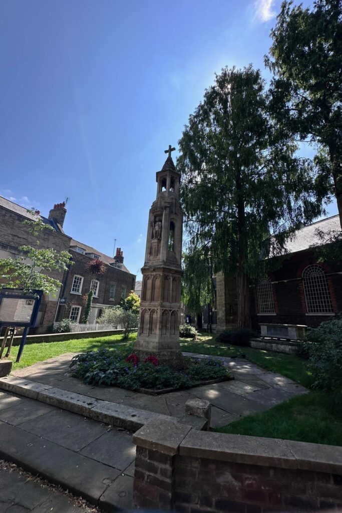 Stone war memorial and old yew tree in the churchyard of St Mary Magdalene church in Richmond London