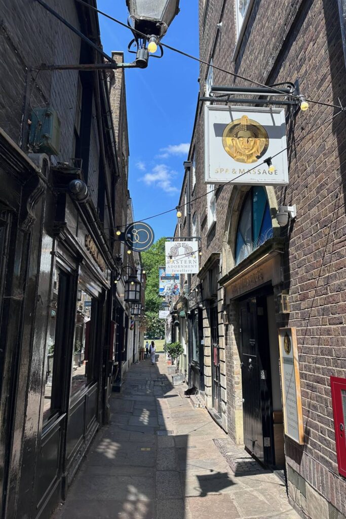 Narrow cobbled Brewer's Lane in Richmond London lined with independent shops and hanging signs