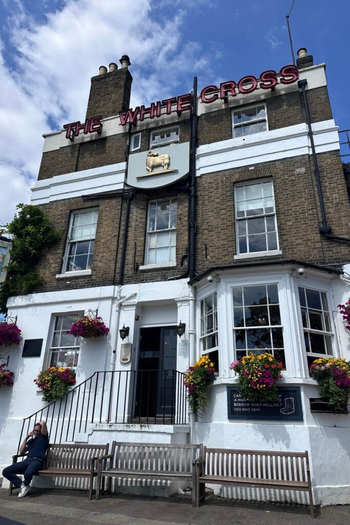 The White Cross pub in Richmond London with hanging flower baskets and a sign offering wellies at high tide