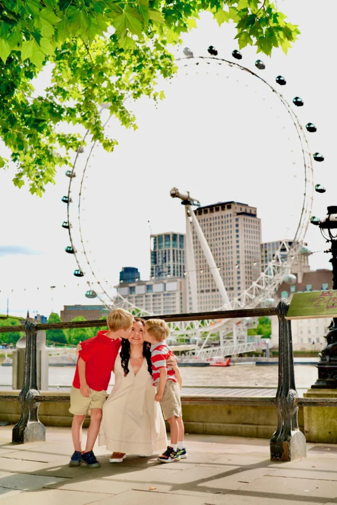 Mom getting a kiss from both sons in front of the London Eye on the South Bank.