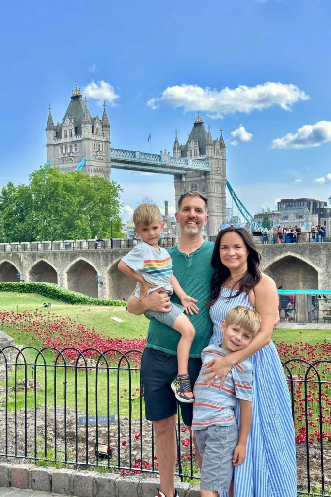 Family of four with Tower Bridge behind them and the ceramic poppy display in the Tower of London moat.