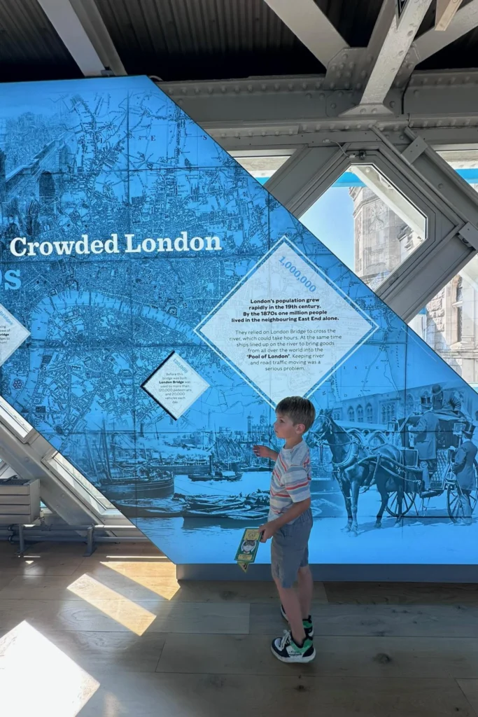 Boy reading the Crowded London exhibit display inside the Tower Bridge walkway.