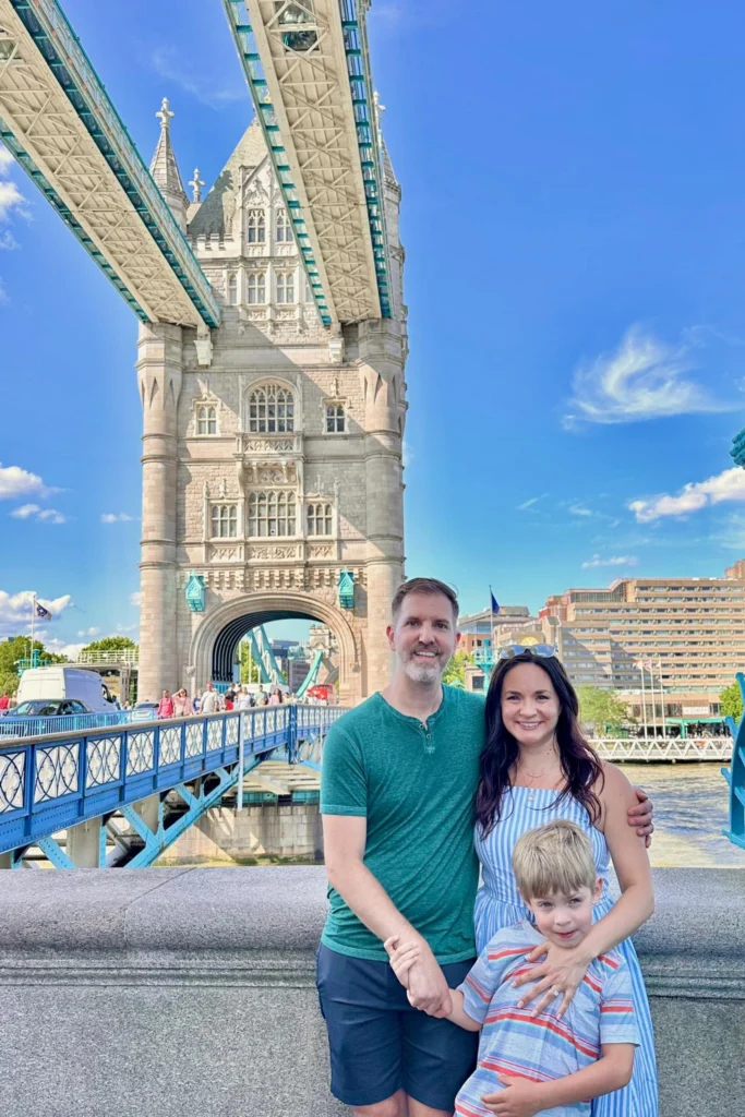 Family standing in front of Tower Bridge in London with the bridge behind them.