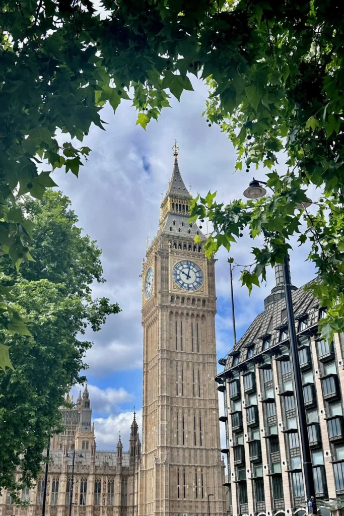 Big Ben framed by green summer leaves in Westminster, London.