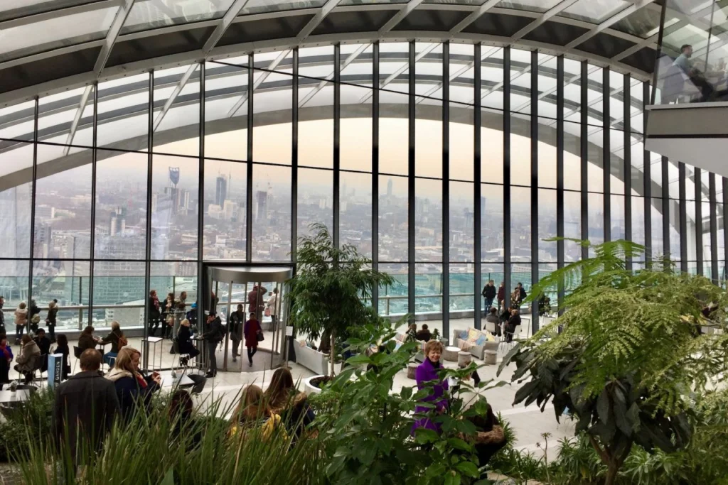 Inside Sky Garden in London, with plants, seating and floor to ceiling windows over the city.